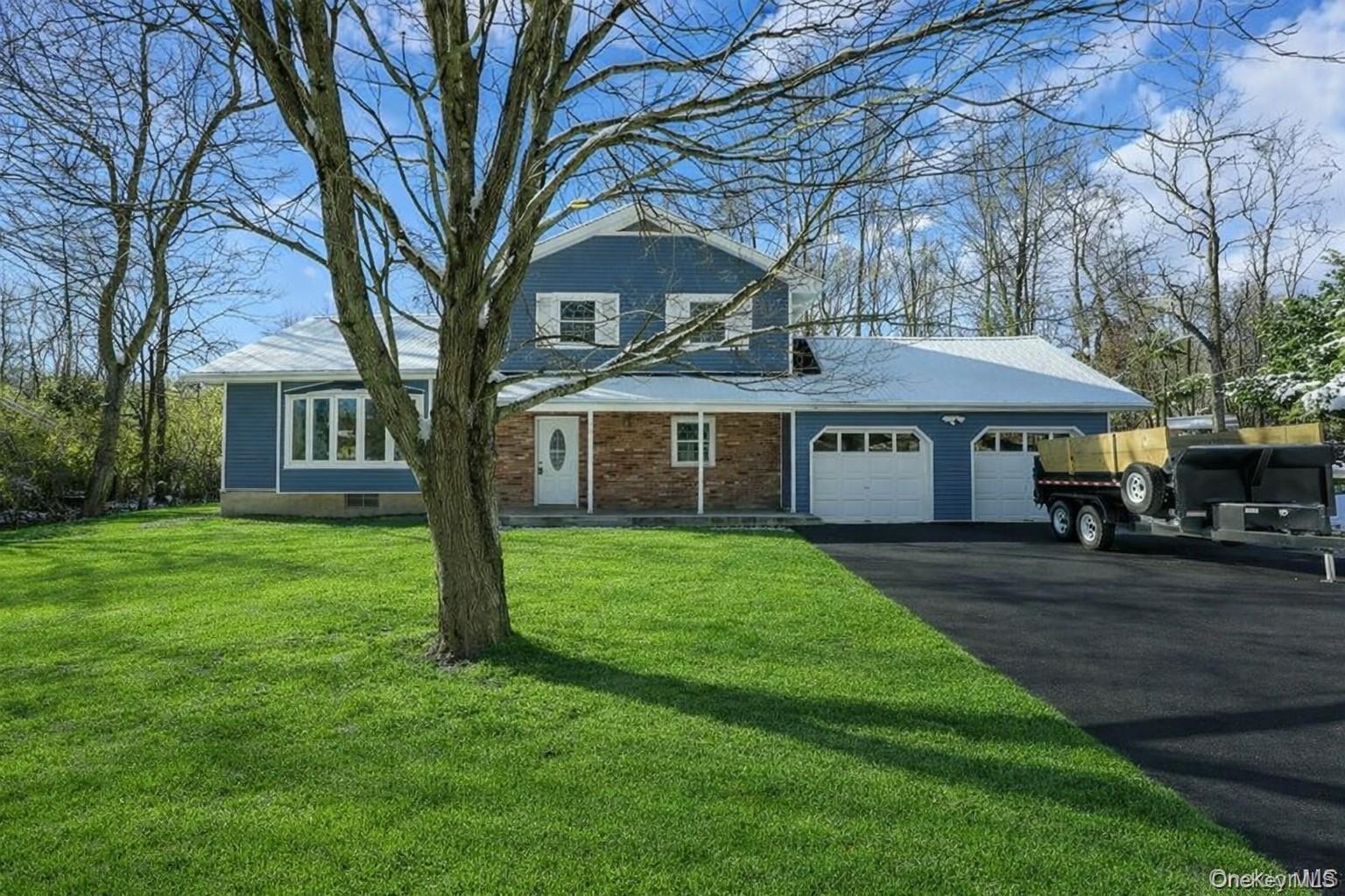 View of front of house with a garage, a front yard, asphalt driveway, and brick siding
