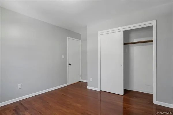 a view of an empty room with wooden floor and a bathroom