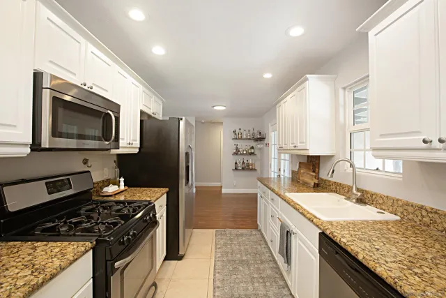 a large kitchen with stainless steel appliances granite countertop a sink stove and refrigerator