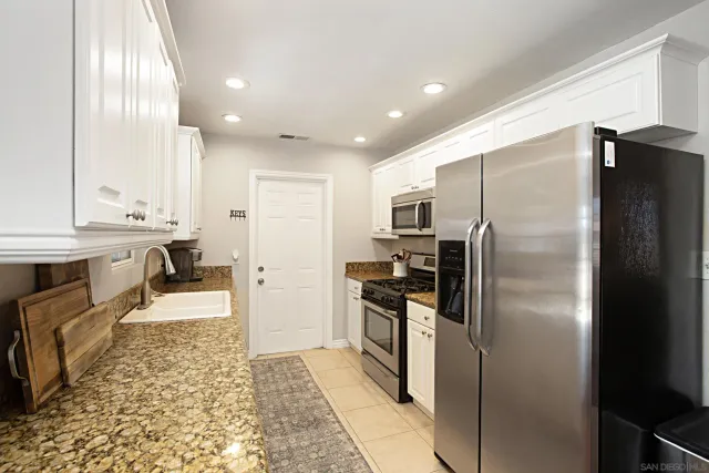 a kitchen with stainless steel appliances granite countertop a refrigerator a sink and a stove