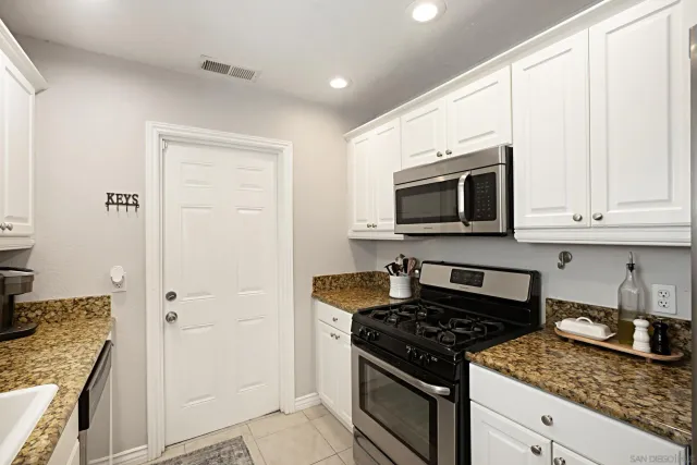 a kitchen with stainless steel appliances granite countertop white cabinets and black stove top oven with granite countertops