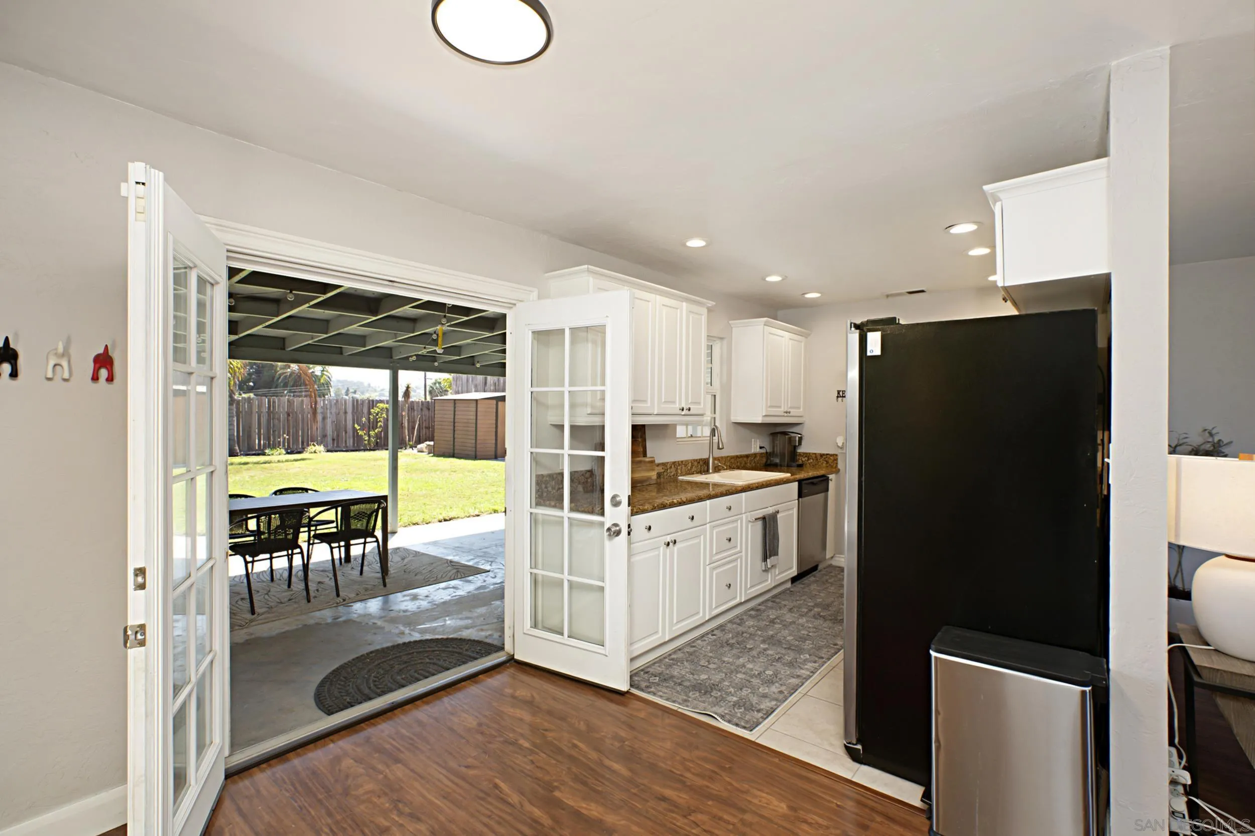 8823 Kelburn Avenue Spring Valley, CA 91977 - Photo 21 of 34 a kitchen with granite countertop a refrigerator a stove a sink and white cabinets with wooden floor
