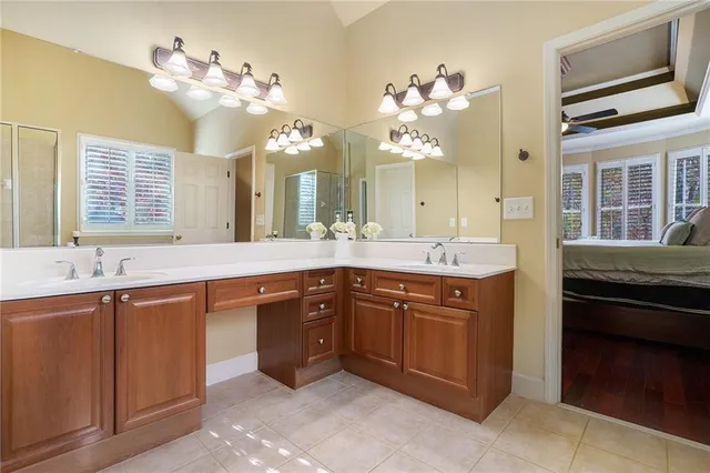 a spacious bathroom with a granite countertop sink a large mirror and a dishwasher with wooden floor