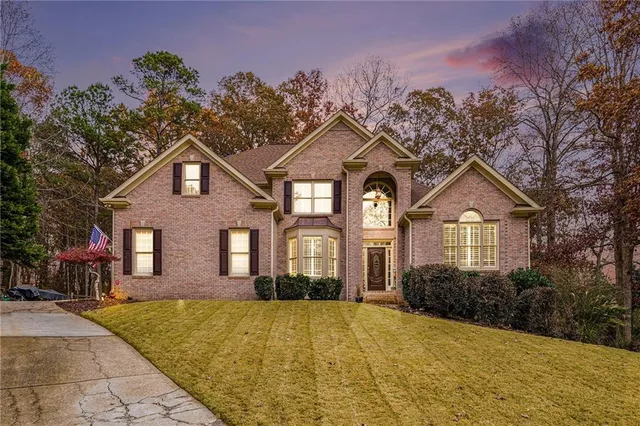 a front view of a house with a yard and trees