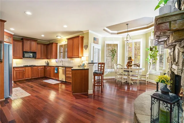 a living room with stainless steel appliances granite countertop furniture wooden floor and a view of kitchen