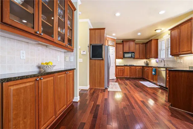 a dining hall with stainless steel appliances granite countertop a refrigerator and a stove top oven