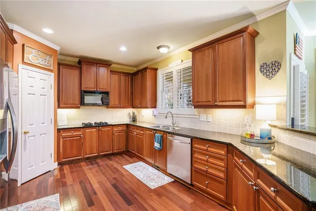 a kitchen with stainless steel appliances granite countertop wooden cabinets a sink and dishwasher a stove with wooden floor