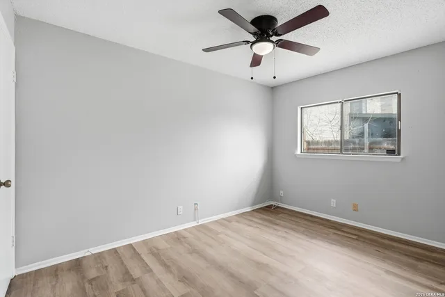 an empty room with a window and a fan