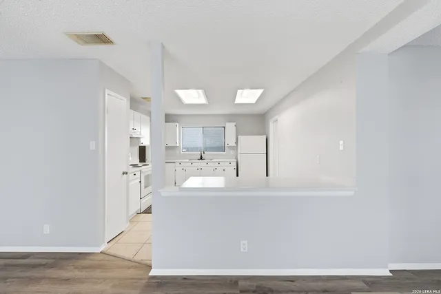 a view of a kitchen with kitchen island a sink wooden floor and living room