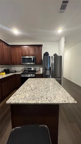 a kitchen with kitchen island granite countertop a refrigerator stove and sink