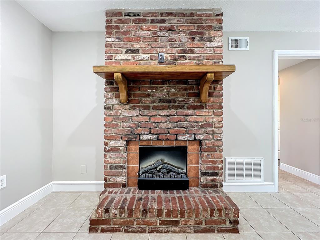 600 Ridgefield Avenue Ocoee, FL 34761 - Photo 13 of 45 Electric Fireplace in living room with ceramic tile floors, upgraded baseboards, new ceiling fan and insulated beveled glass front door opens to dinging area and kitchen.