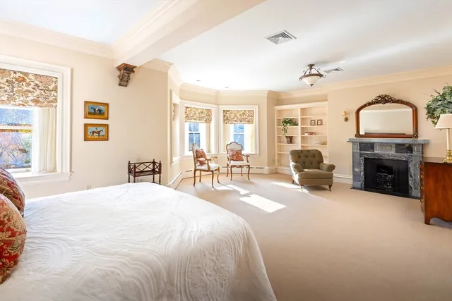 a spacious bedroom with a bed a fireplace and a chandelier