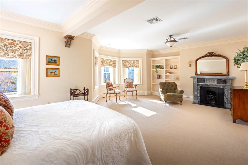 129 Commonwealth Avenue, Unit SF Boston, MA 02116 - Photo 15 of 19 a spacious bedroom with a bed a fireplace and a chandelier