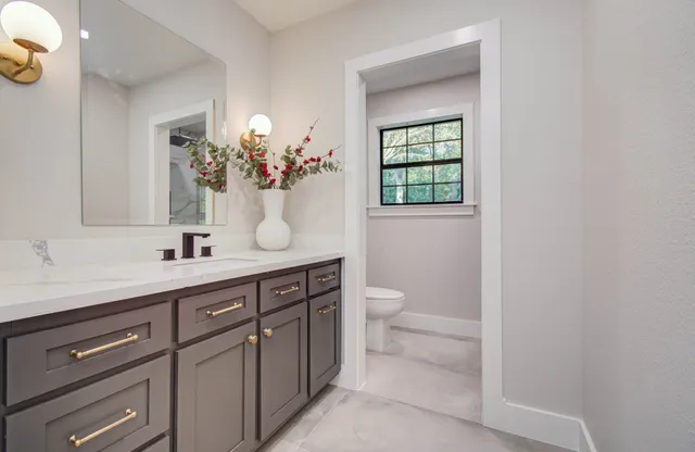 a bathroom with a toilet a sink a mirror and a window