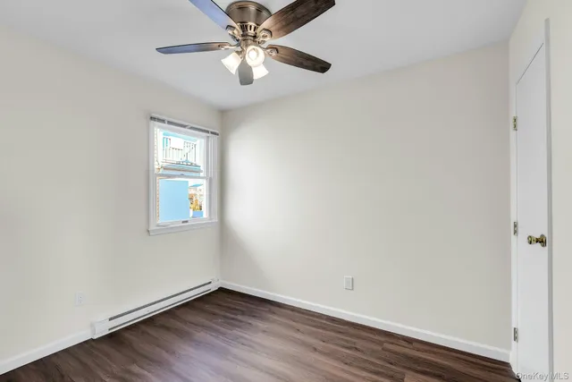 an empty room with wooden floor chandelier fan and windows
