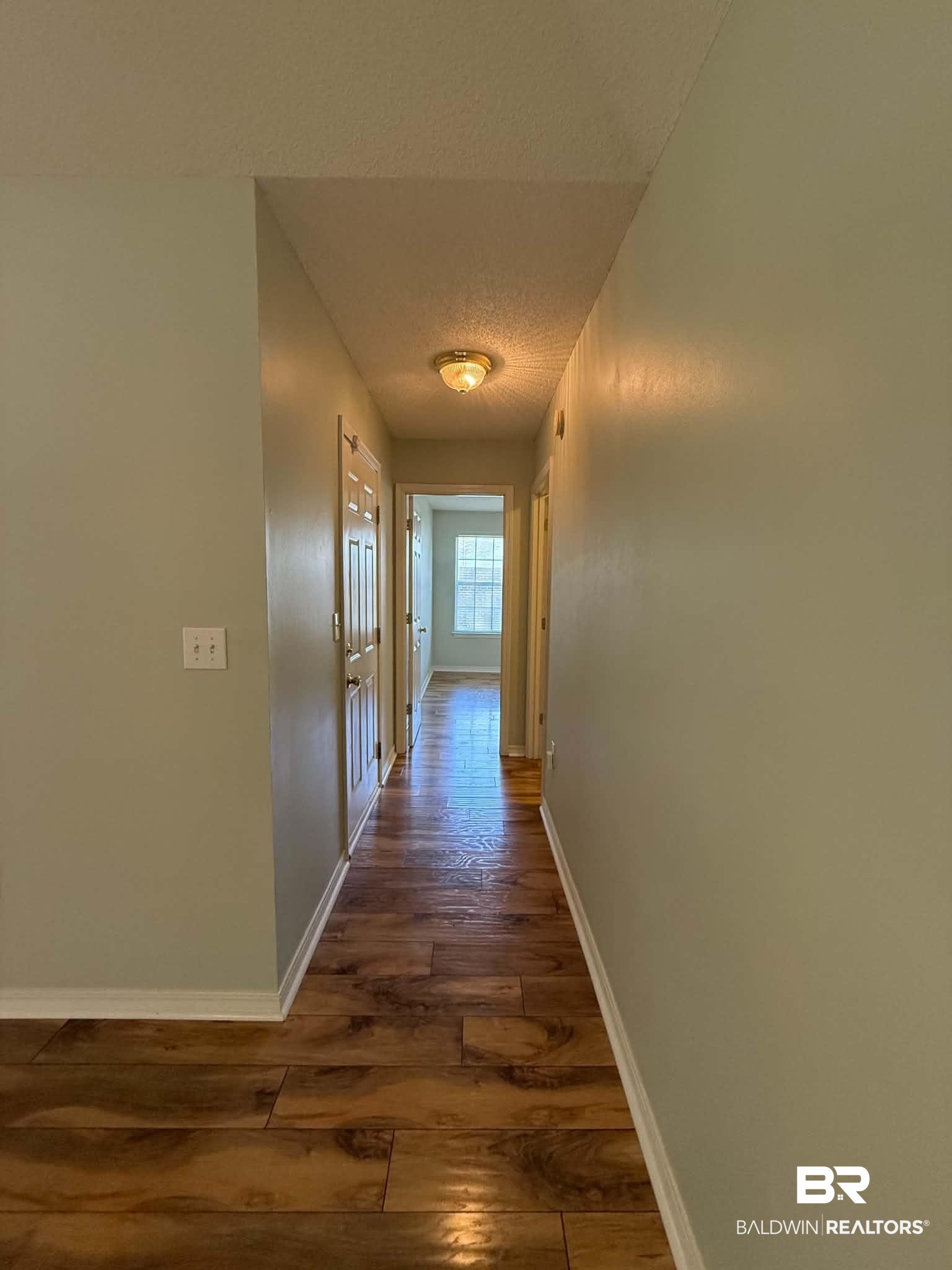 123 Pennbrooke Loop Foley, AL 36535 - Photo 38 of 49 Hallway featuring wood-finish flooring, light-toned wall paint, white baseboards, and a flush-mount ceiling light fixture