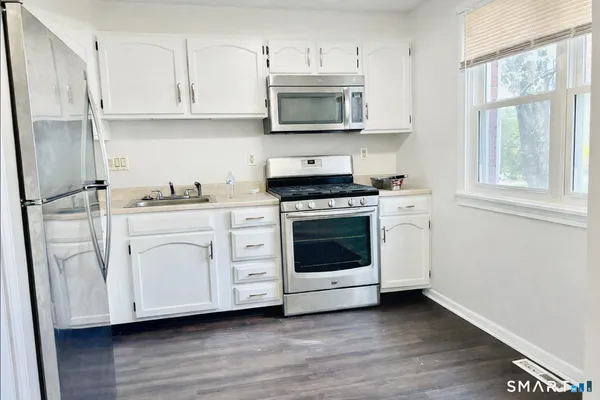 a kitchen with stainless steel appliances white cabinets and a wooden floor