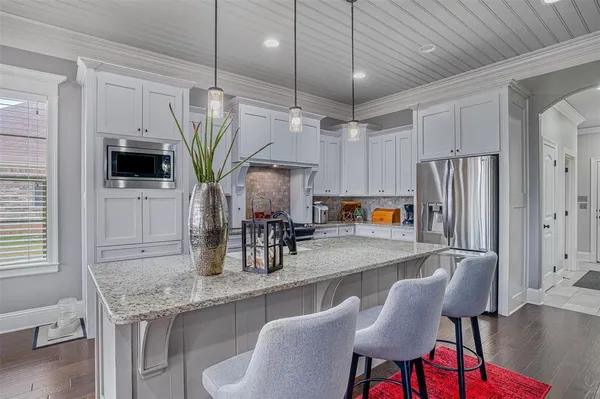a kitchen with stainless steel appliances granite countertop a table chairs in it and wooden floors