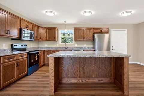 a kitchen with granite countertop wooden cabinets and white appliances