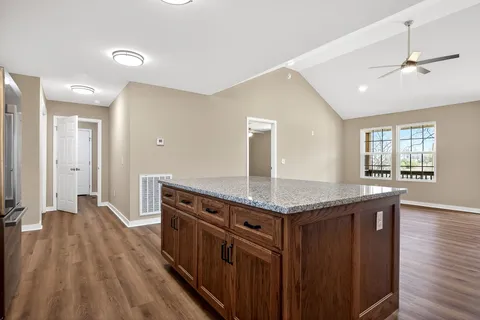 a kitchen with stainless steel appliances granite countertop a stove a sink dishwasher and a refrigerator with wooden floor