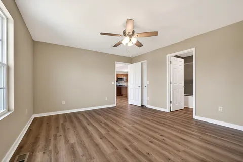 a view of empty room with wooden floor and fan