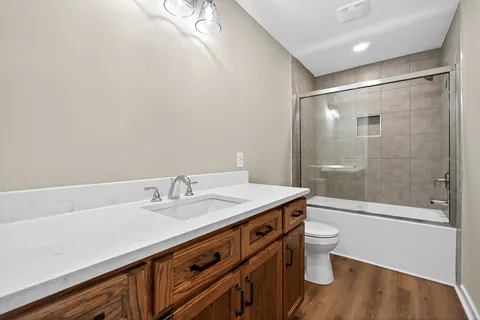 a bathroom with a granite countertop sink a toilet a mirror and shower