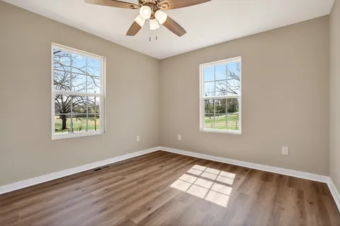 a view of an empty room with wooden floor and window