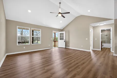 a view of an empty room with window and wooden floor