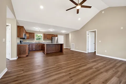 a view of an empty room with kitchen and window