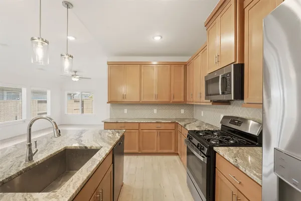 a kitchen with granite countertop a sink stainless steel appliances and cabinets