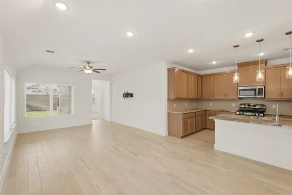 a kitchen with stainless steel appliances granite countertop a stove a sink dishwasher and a refrigerator with wooden floor