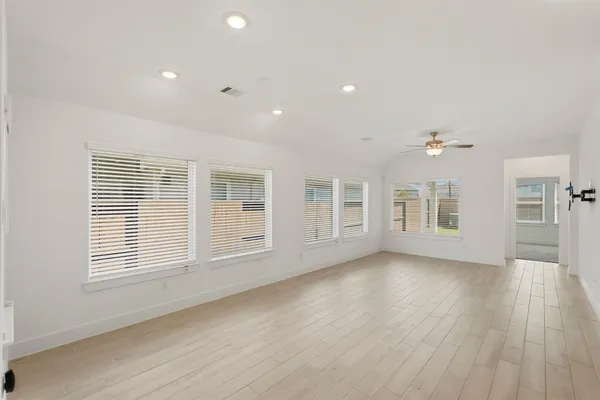 an empty room with wooden floor and windows