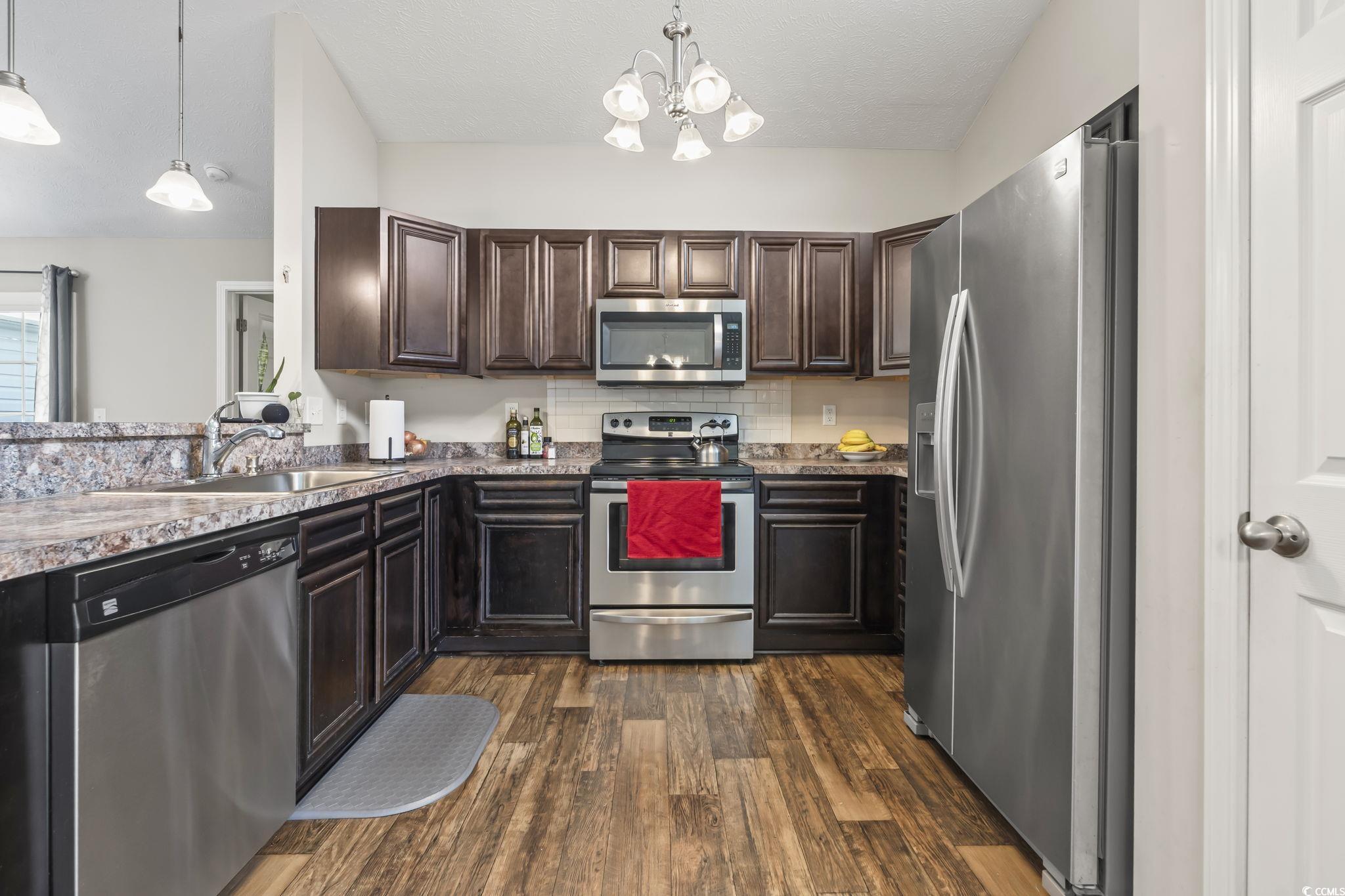 282 Foxpath Loop Myrtle Beach, SC 29588 - Photo 12 of 34 Kitchen featuring appliances with stainless steel finishes, a sink, dark brown cabinets, and dark wood finished floors