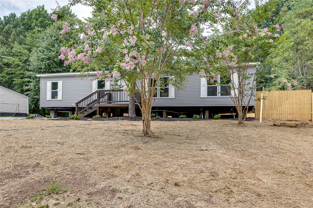 474 Bryant Road Pelzer, SC 29669 - Photo 4 of 42 Mature trees and newly installed fencing frame this charming elevated residence, blending natural beauty with privacy.