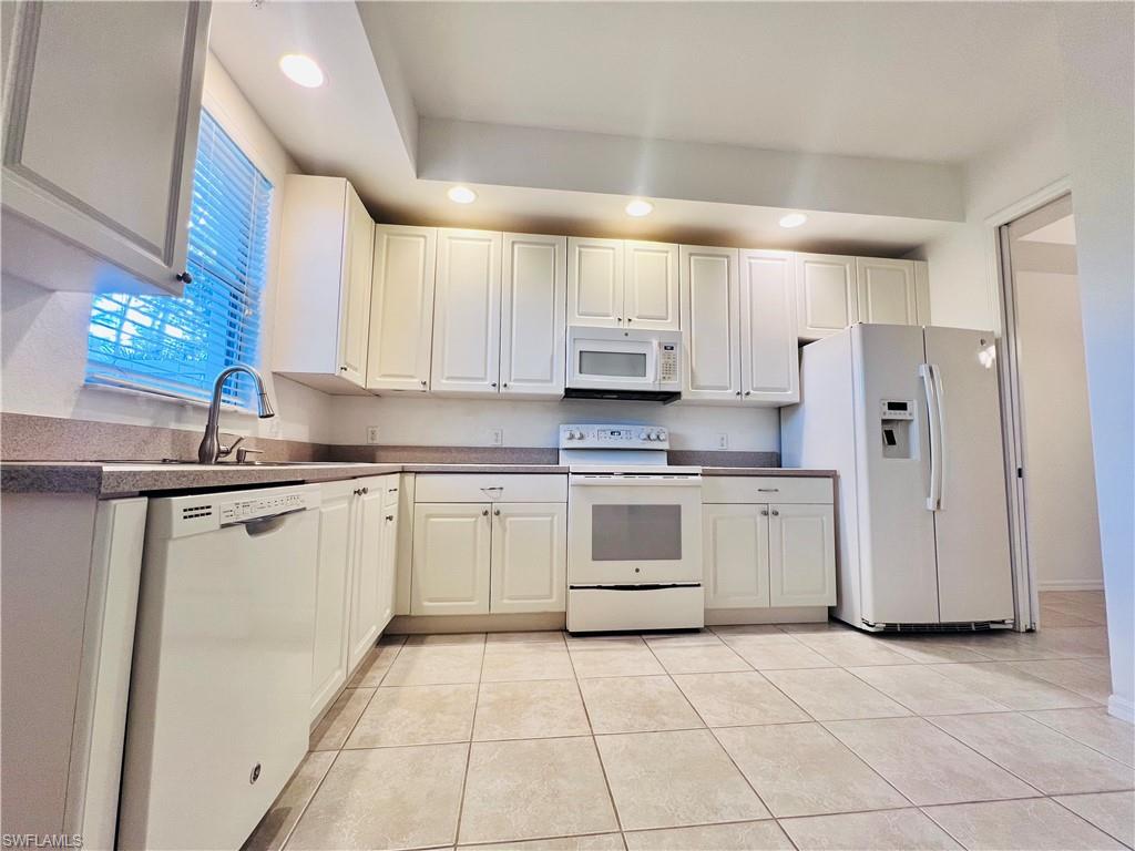 1435 Mariposa Circle, Unit 102 Naples, FL 34105 - Photo 7 of 24 a kitchen with white cabinets and white appliances