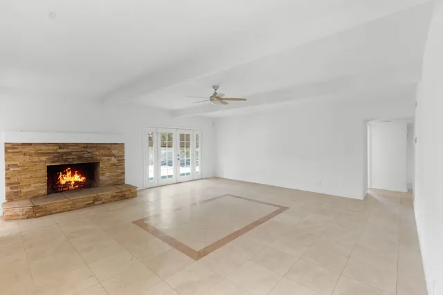 an empty room with windows and fireplace