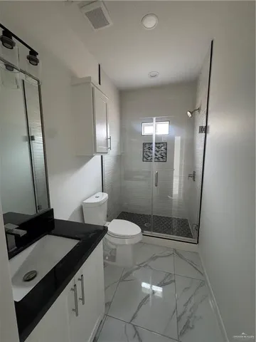a bathroom with a sink a toilet a mirror and shower