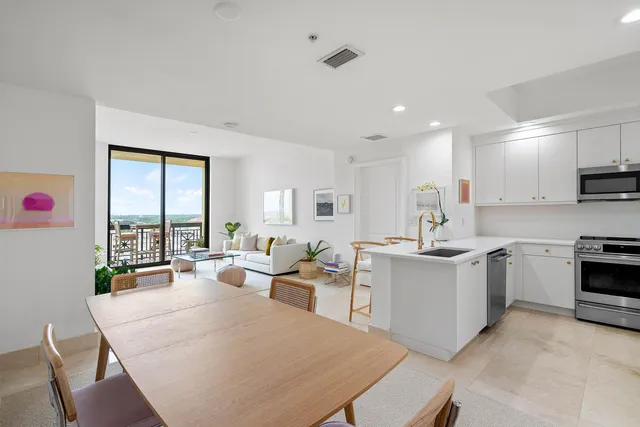 a large white kitchen with a stove a sink a microwave a dining table and chairs