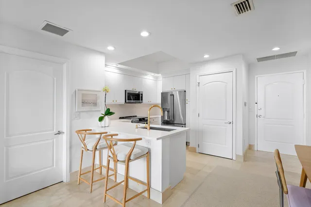 a kitchen with stainless steel appliances a refrigerator a stove a microwave a dining table and chairs