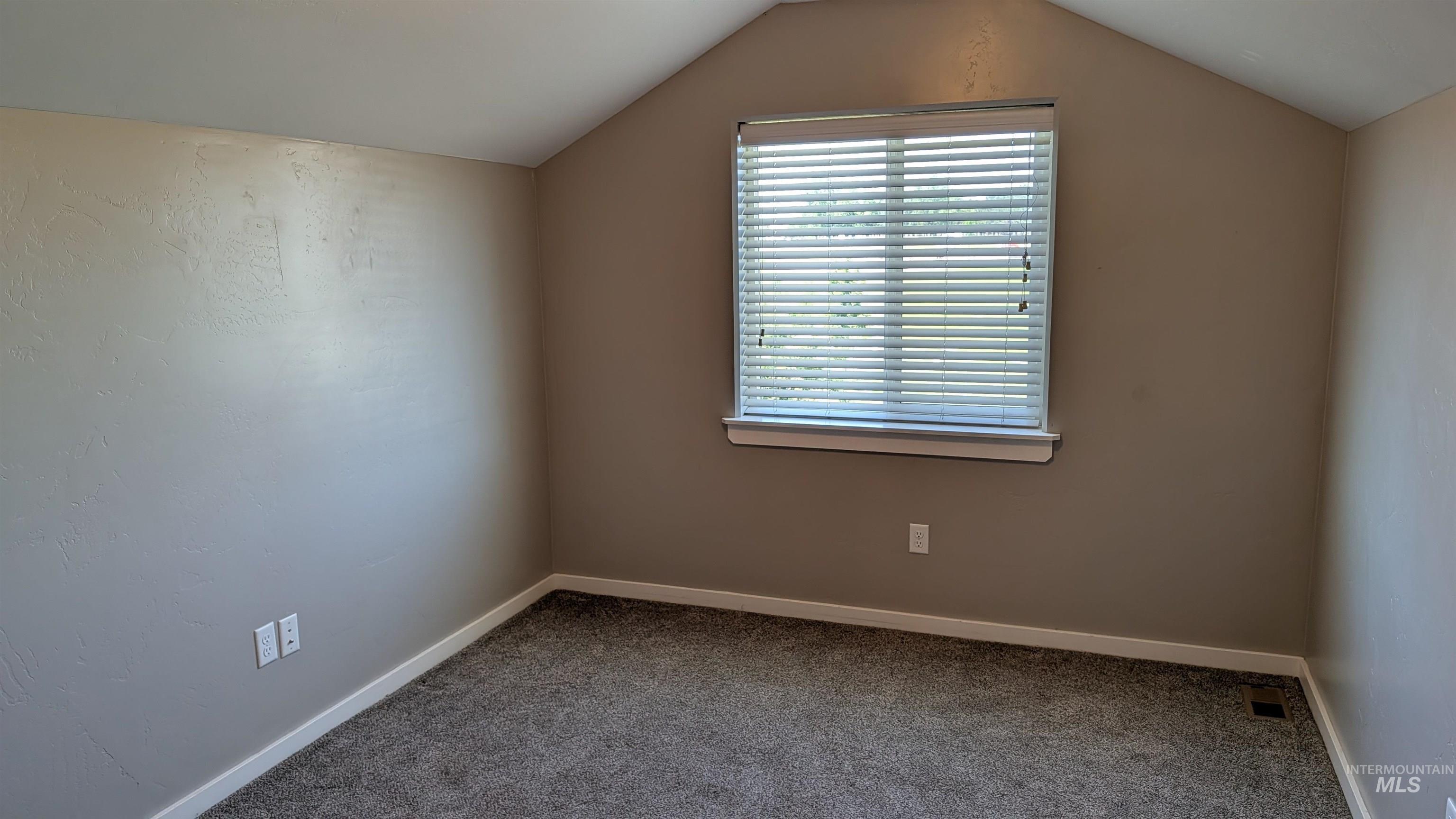 622 Lochsa Loop Heyburn, ID 83336 - Photo 14 of 17 Neutral-toned room featuring a single window with blinds, vaulted ceilings, and plush gray carpeting