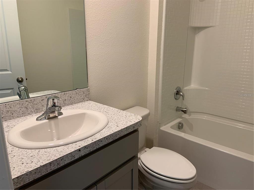 5518 Oxford Gray Road Wesley Chapel, FL 33545 - Photo 11 of 11 a bathroom with a granite countertop sink toilet and bathtub