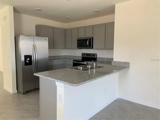 a kitchen with stainless steel appliances granite countertop a sink a microwave a refrigerator and a stove