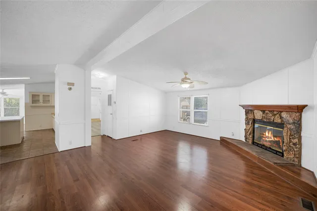 an empty room with wooden floor fireplace and windows