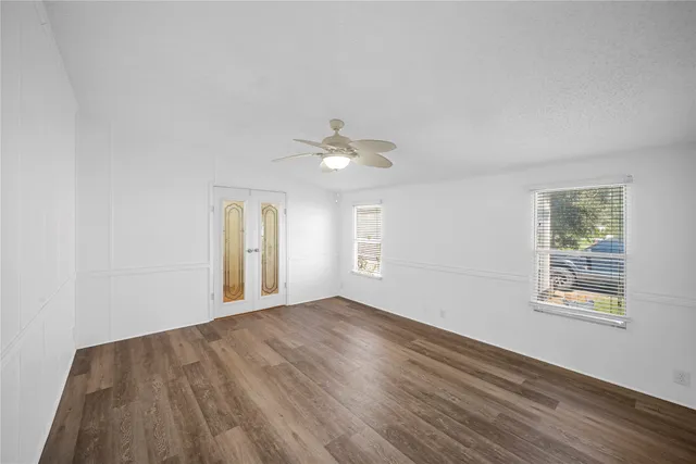 a view of an empty room with wooden floor and a window