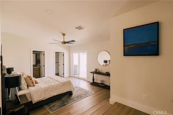 a bedroom with bed tv and wooden floor