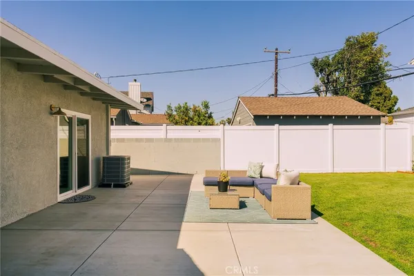 a view of a patio with couches table and chairs under an umbrella