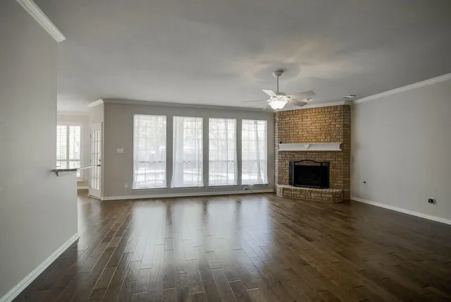 an empty room with wooden floor fireplace and windows