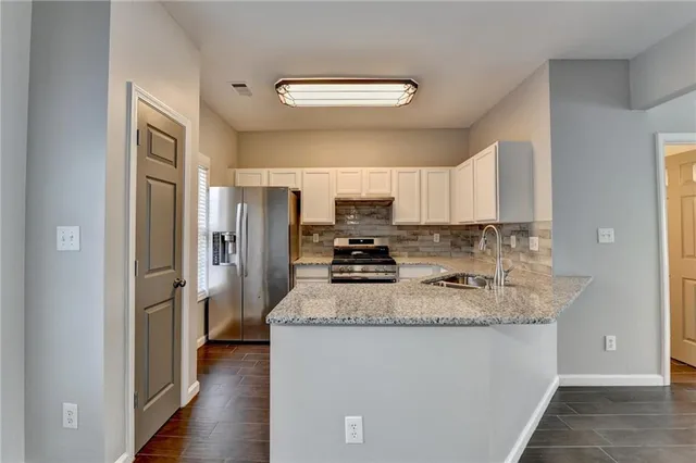 a kitchen with stainless steel appliances granite countertop a refrigerator a stove top oven a sink and dishwasher