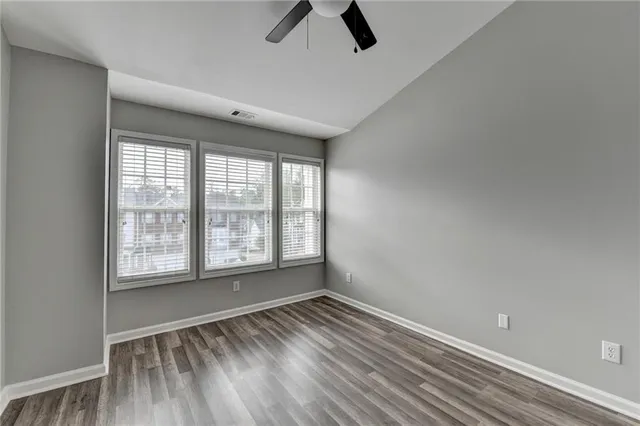an empty room with wooden floor closet and ceiling fan