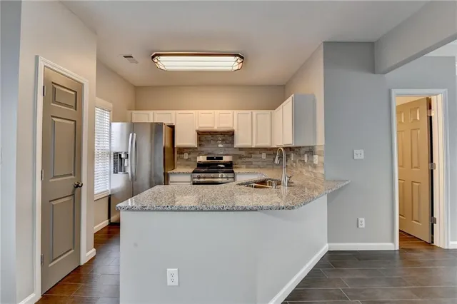 a kitchen with stainless steel appliances granite countertop a refrigerator a stove and a sink